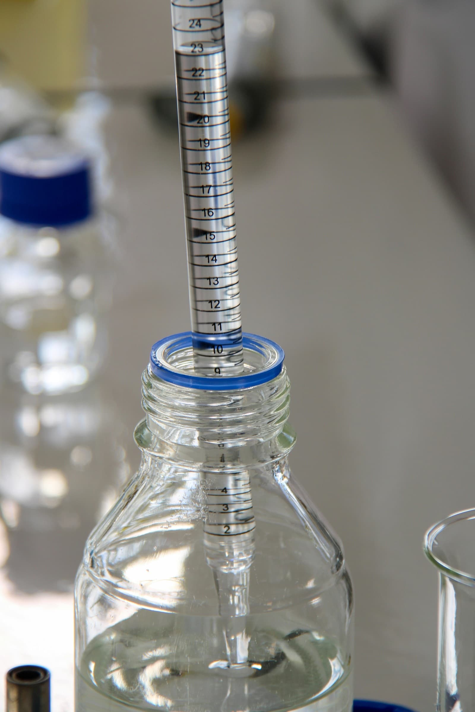Pipette dispensing clear liquid into a glass bottle